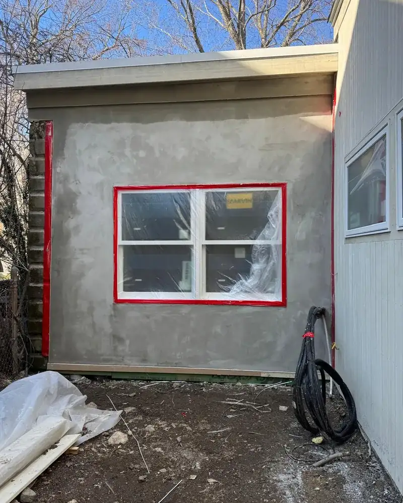 Stucco brown coat leveled around a new window on an exterior addition